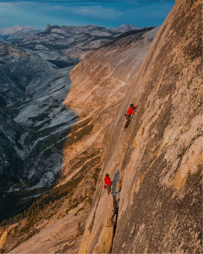 Two people in red jackets climbing a mountain